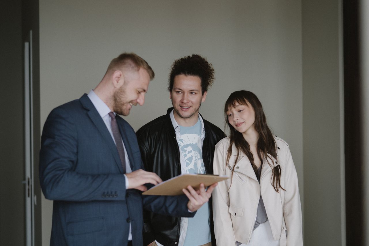 Offerings Happy couple meeting with a real estate agent discussing paperwork indoors.