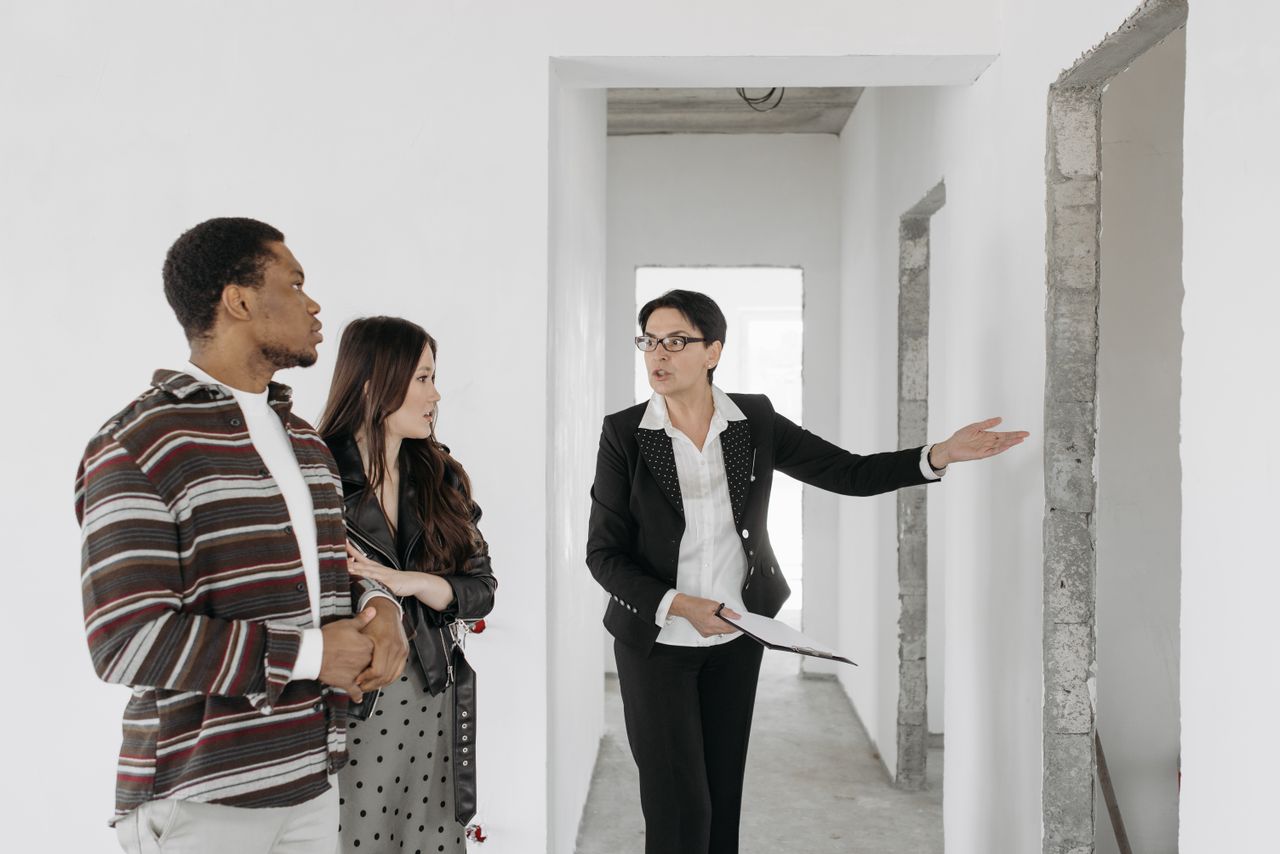 Home Real estate agent shows a house to a couple, discussing features.